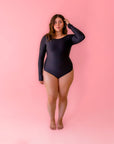 A black one piece, long sleeve swim suit with cut outs on the hips.