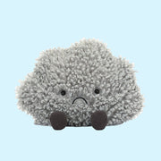 ON a blue background is a grey storm cloud shaped stuffed toy.