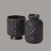 A photo of the black spider pot and the black raven vase next to one another. Sold separately.