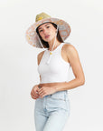 On a white background is a neutral colored straw sun hat with a neckstrap and a light pink and light orange sun design on the underside of the brim.