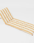 A mustard and ivory striped unfoldable beach or pool chair with folds into a compact square with a strap for carrying.