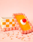 An orange and pink vintage cake shaped storage box made out of ceramic.
