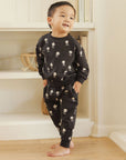 Little boy modeling a black sweatsuit with white skull and crossbones print.