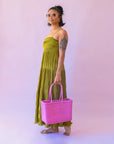 On a pink background is a hot pink woven bag.