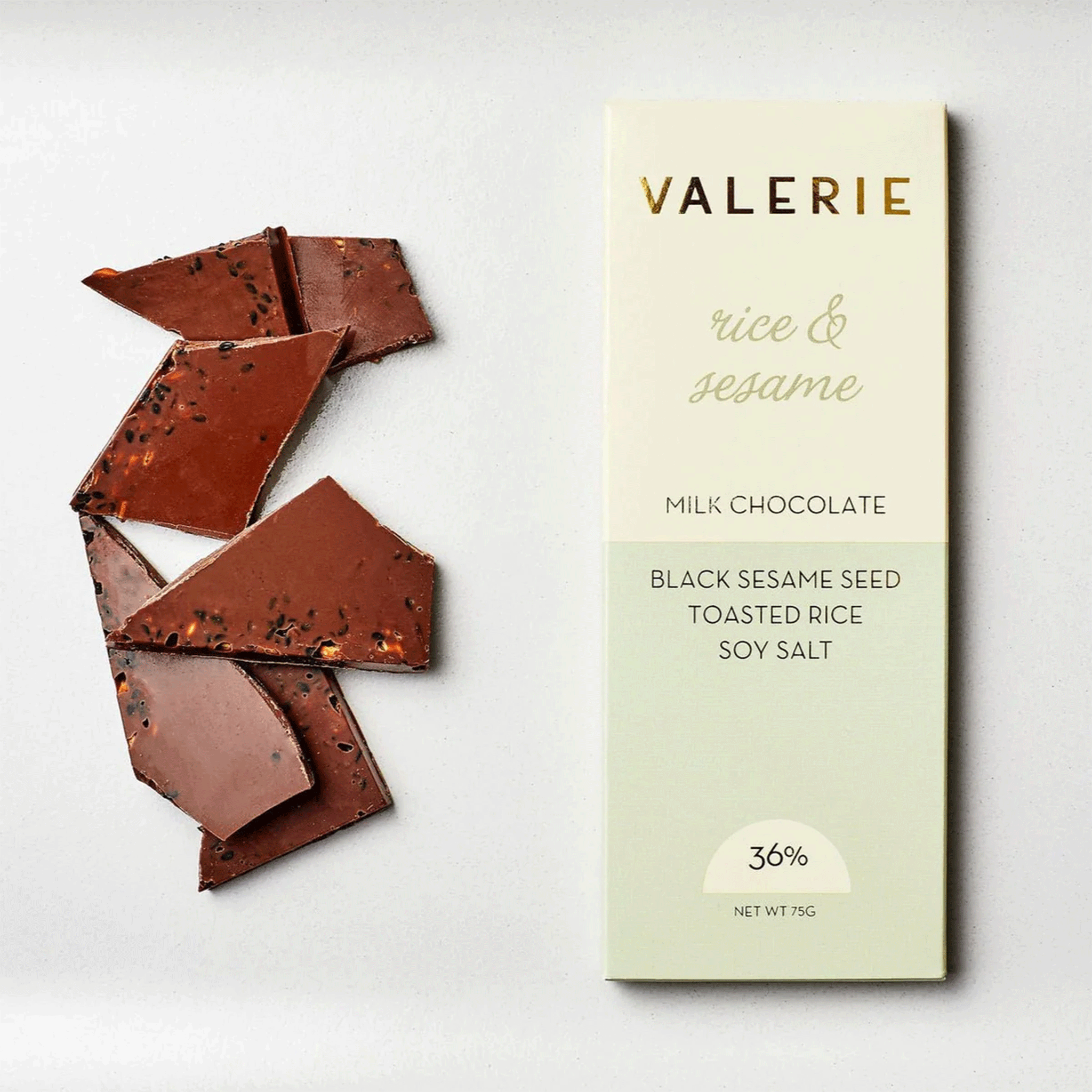 On a white background is a neutral colored bar of chocolate with gold foiled text that reads, &quot;Valerie rice &amp; sesame Milk Chocolate&quot;.