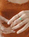 A thin gold ring with a green chrysoprase stone in the center.
