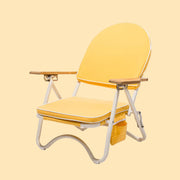 A yellow arched back folding beach chair with wood armrests and white legs. The backside features a zip pocket for storing beachside essentials.