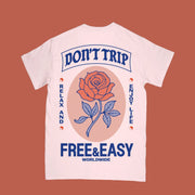 Light pink short-sleeve T-shirt shown from the back with large graphic of a rose and text reading “Don’t Trip,” “Relax and Enjoy Life,” and “Free & Easy Worldwide” in blue and orange.
