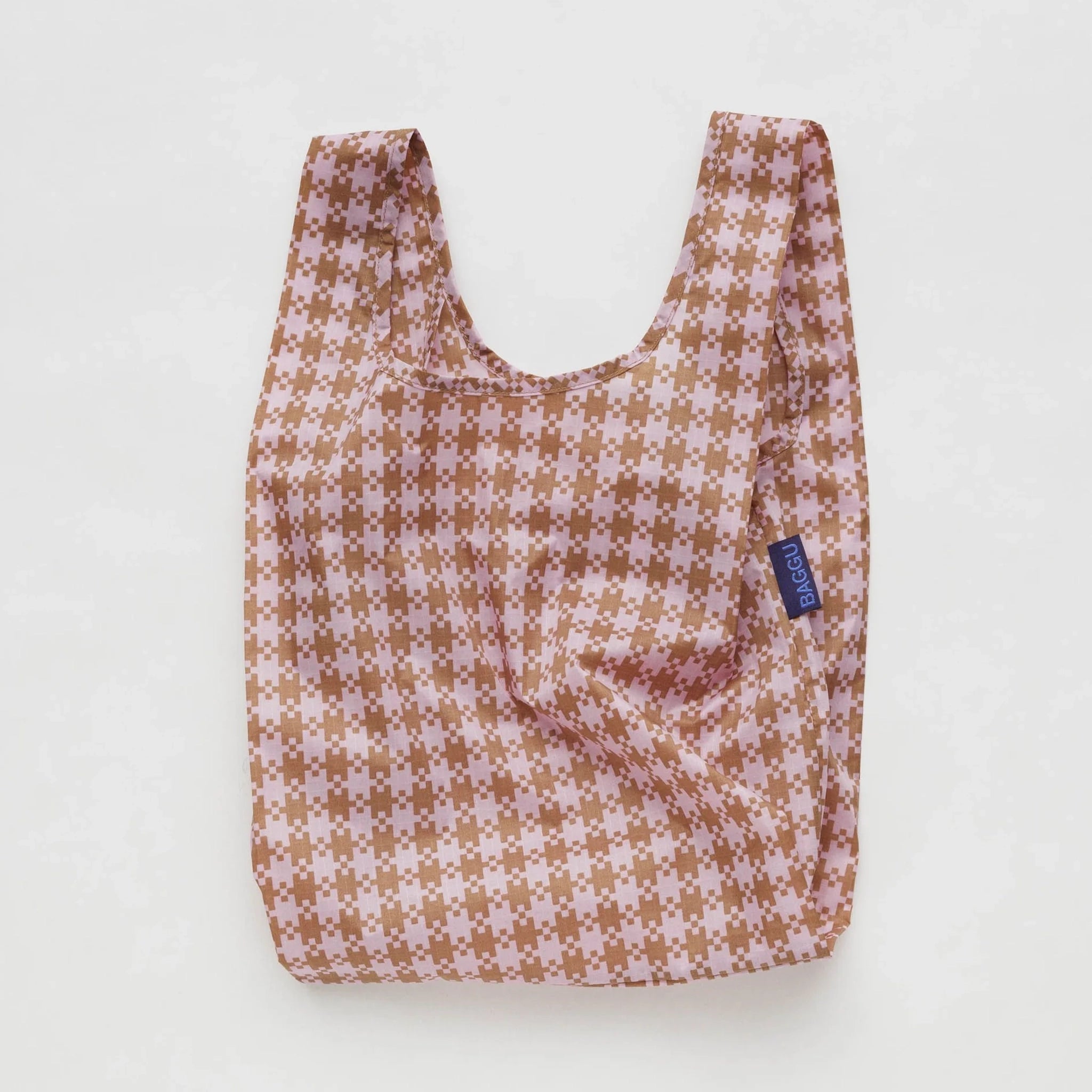 On a white background is a pink and tan gingham print tote bag made out of nylon.