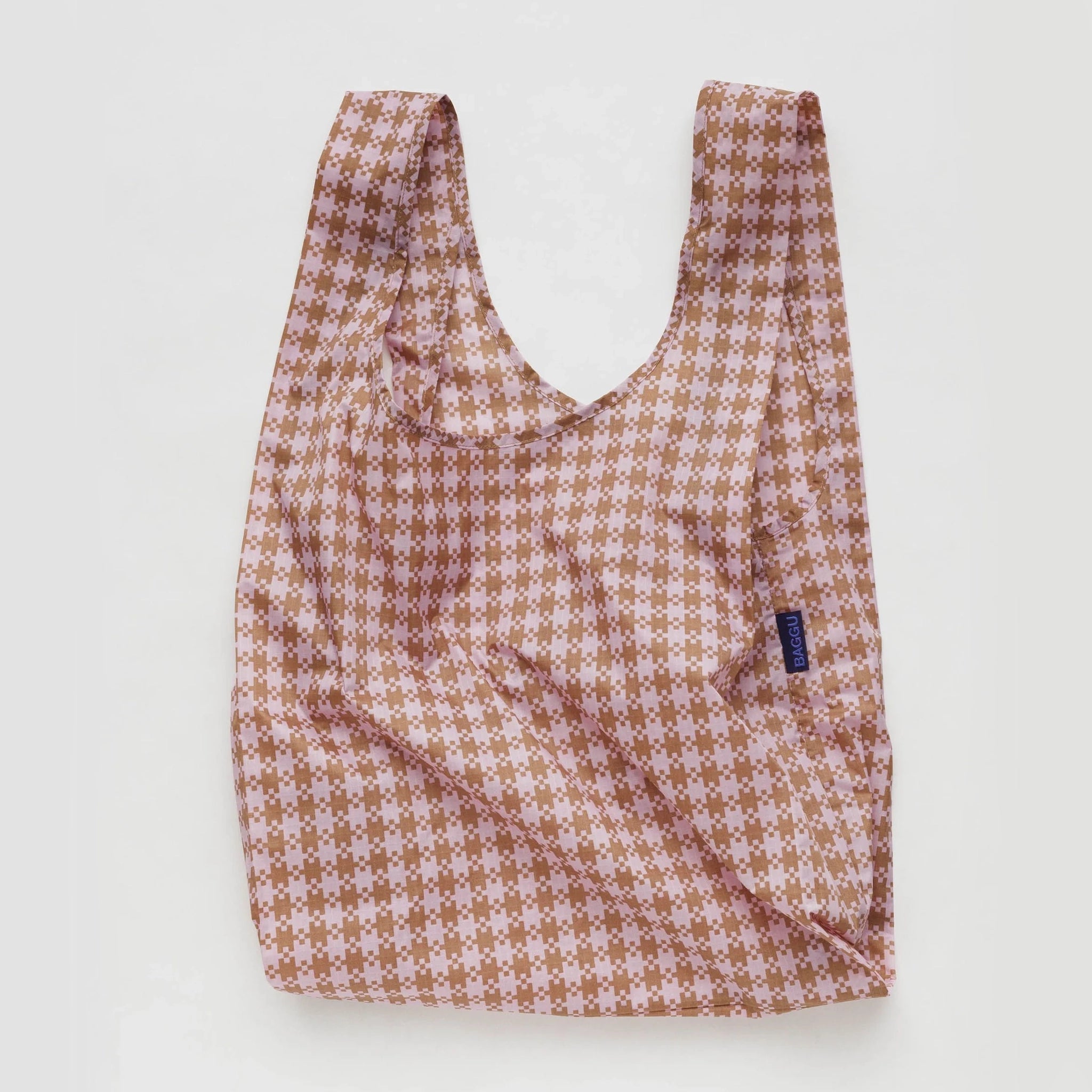 On a white background is a rose colored reusable tote with a gingham print all over. 