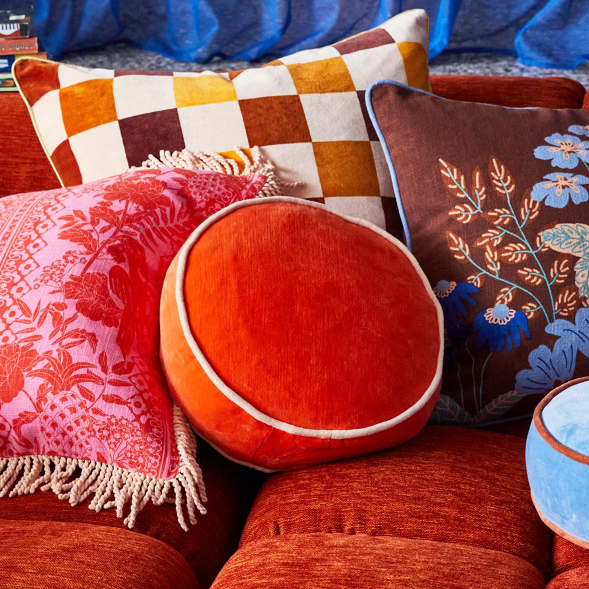 A round orange velvet pillow with an ivory edge.