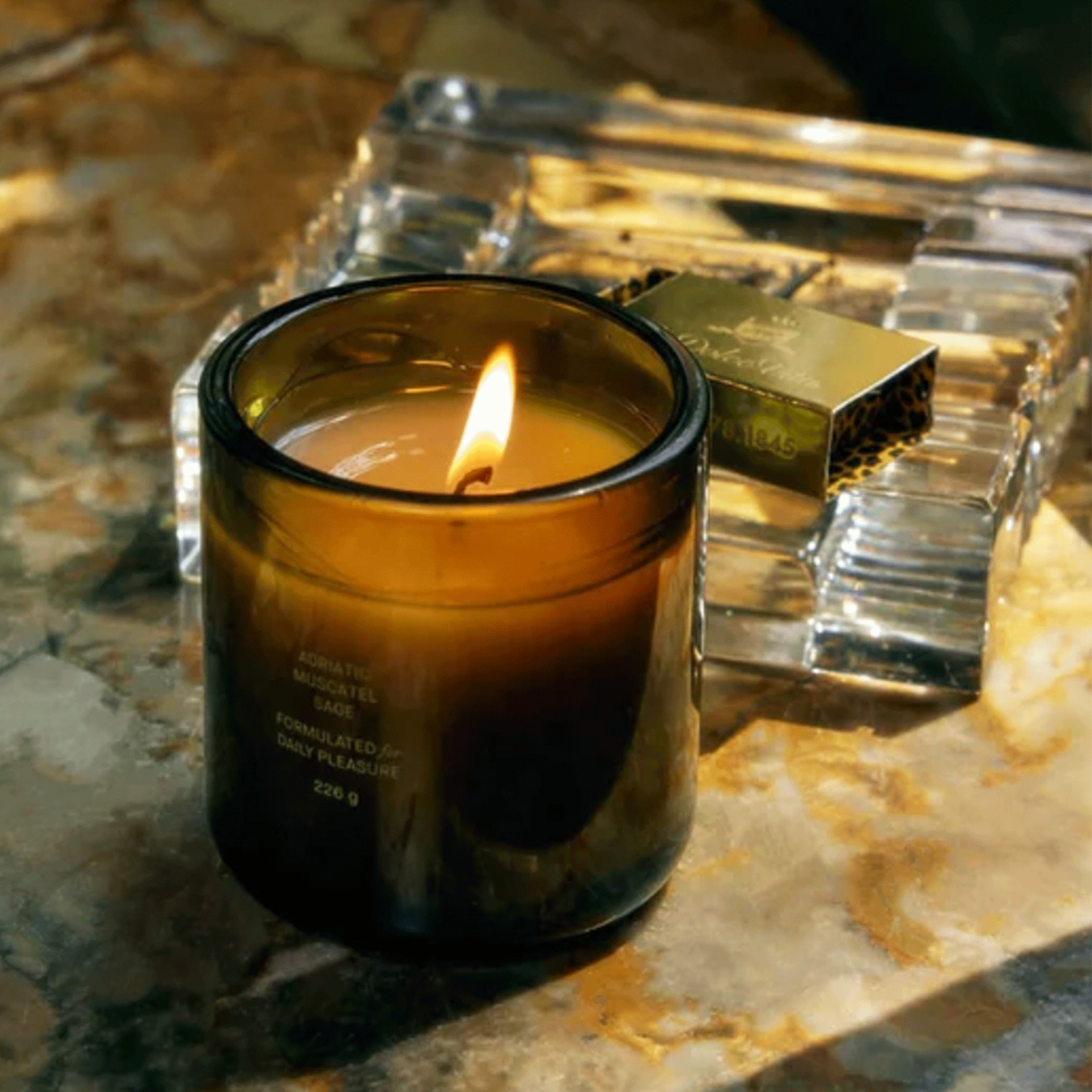 A dark green glass jar candle with a logo in the center that reads, "Flamingo Estate".