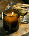 A dark green glass jar candle with a logo in the center that reads, "Flamingo Estate".