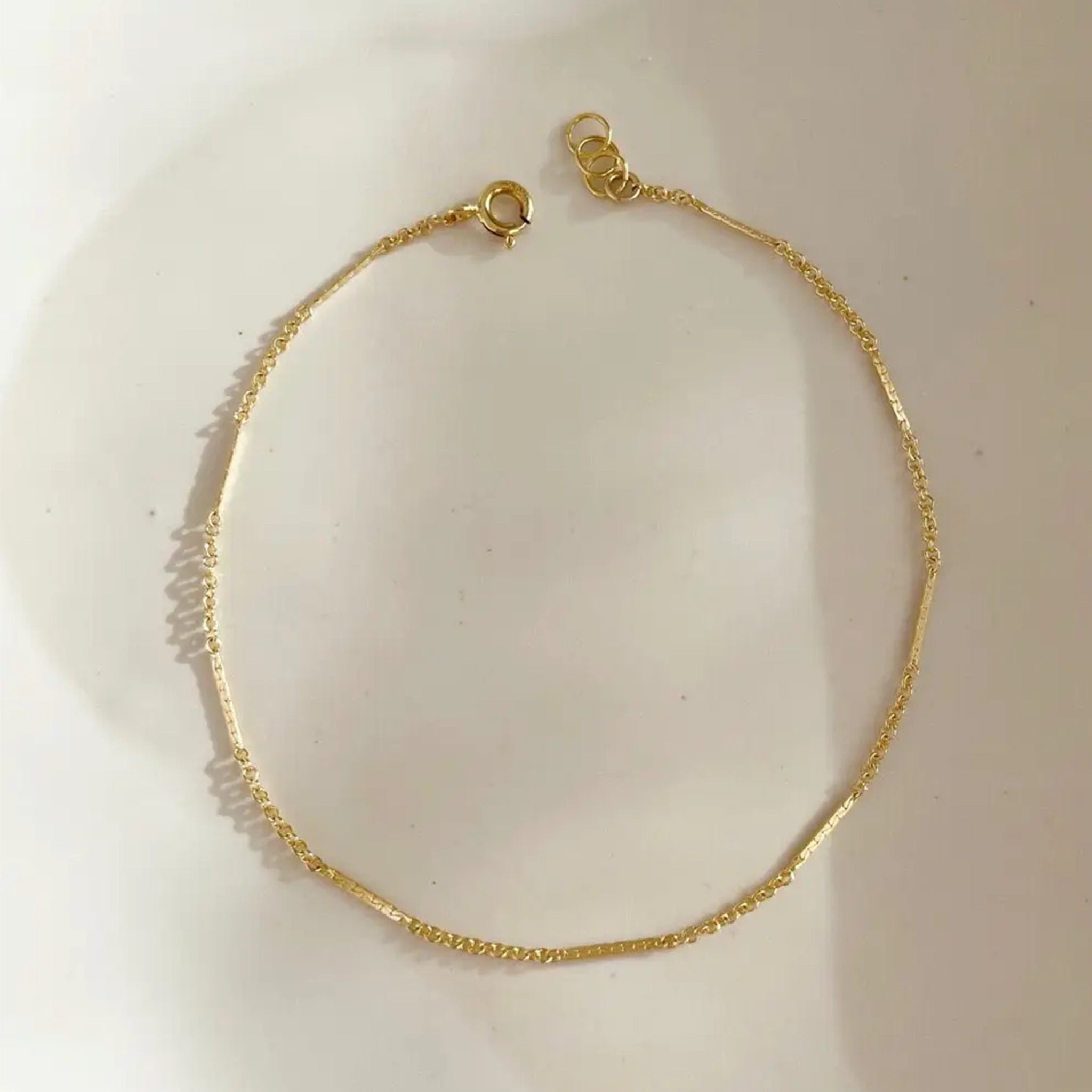 A gold chain bracelet with a round clasp at the end. 