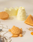A set of five sand moulds in the shape of a shell, a turtle, a sailboat, and a castle.