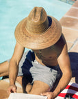 A darker brown straw sun hat with a wide curved brim and a drawstring.