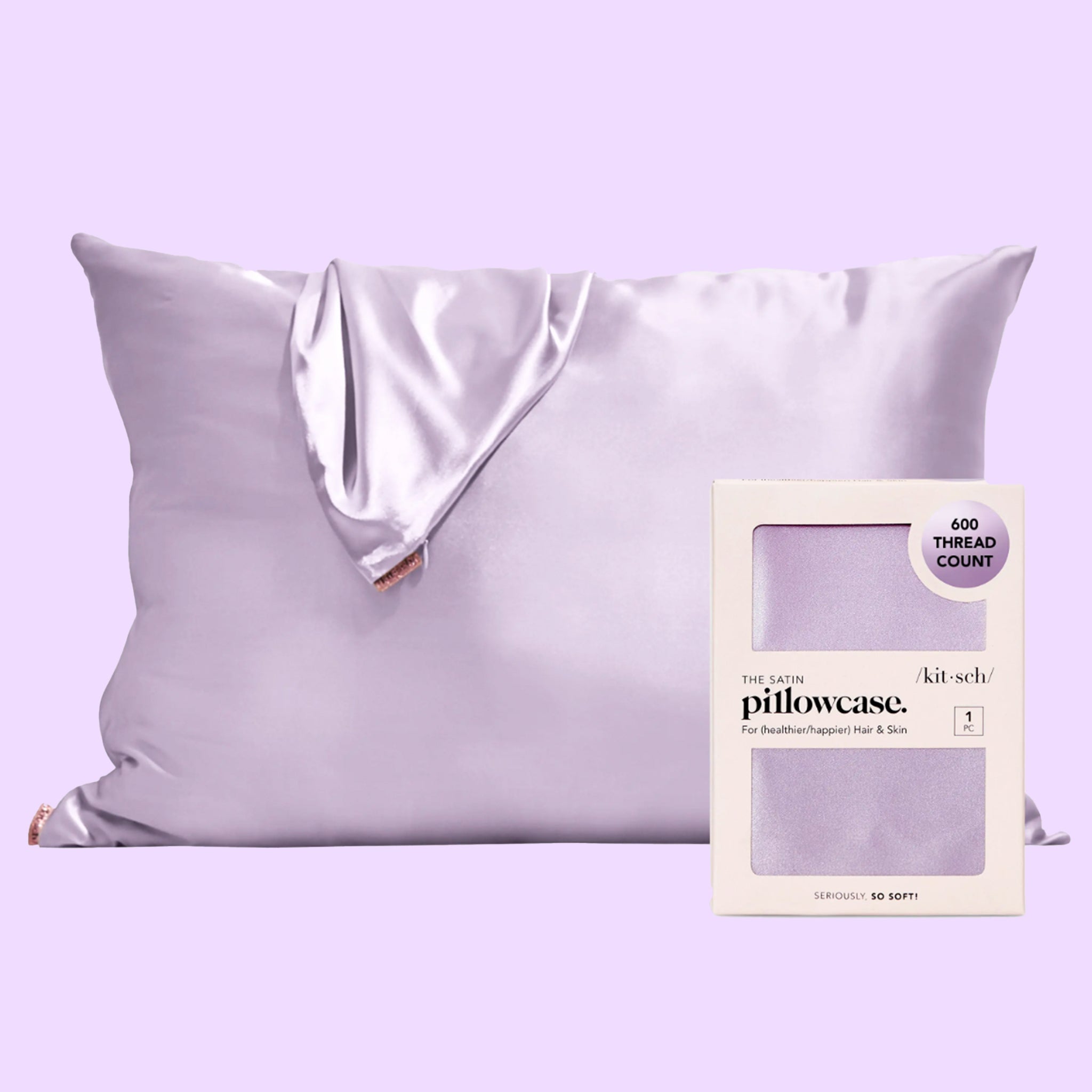 A purple satin pillowcase next to the packaging that it comes in. 
