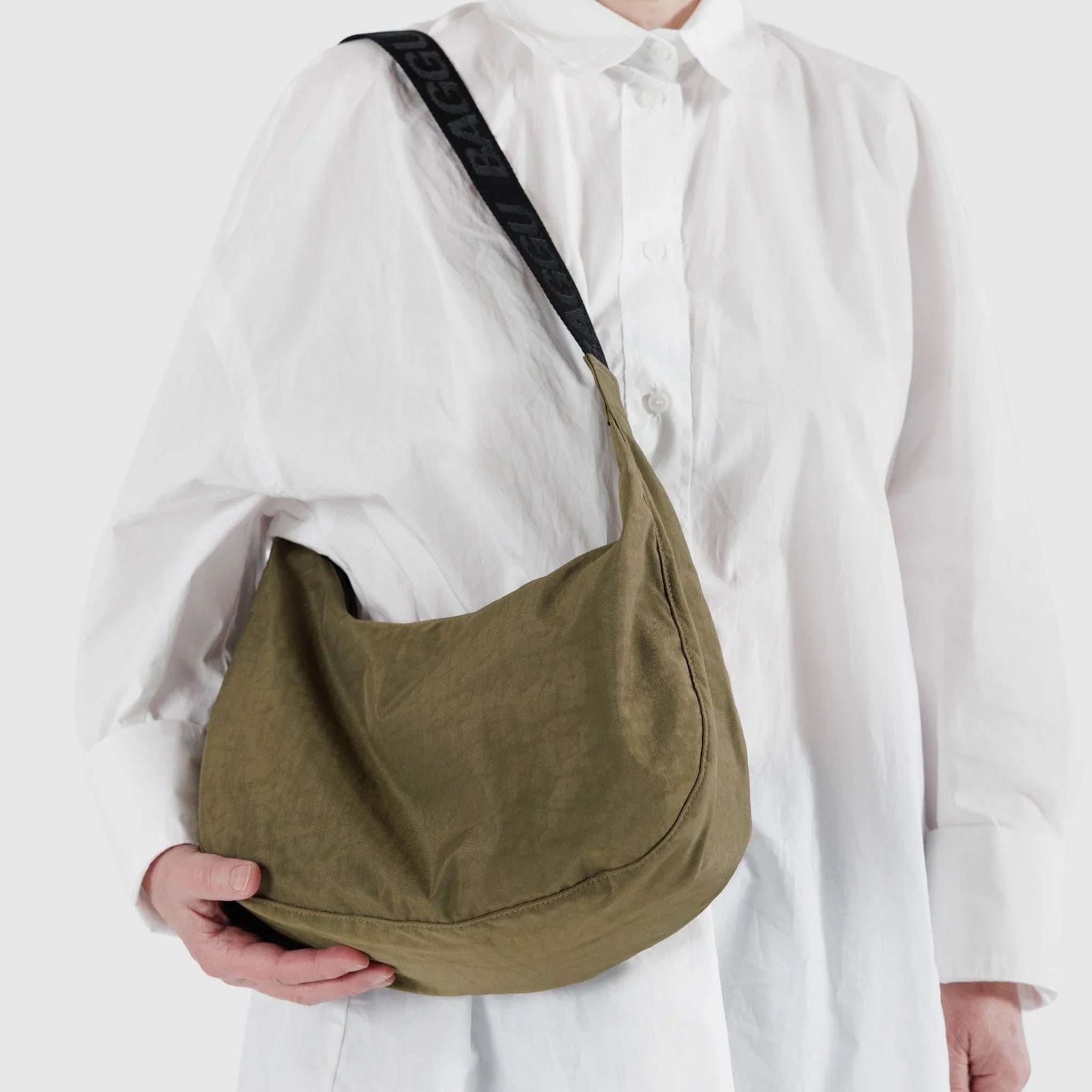 A dark green crescent nylon bag with a black shoulder strap
