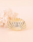 A gold seashell shaped hair clip.