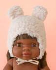 A white sherpa hat with ears on a Minikane doll.