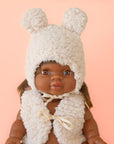 A Minikane doll dressed in a Sherpa vest and hat with ears. Doll and hat sold separately.