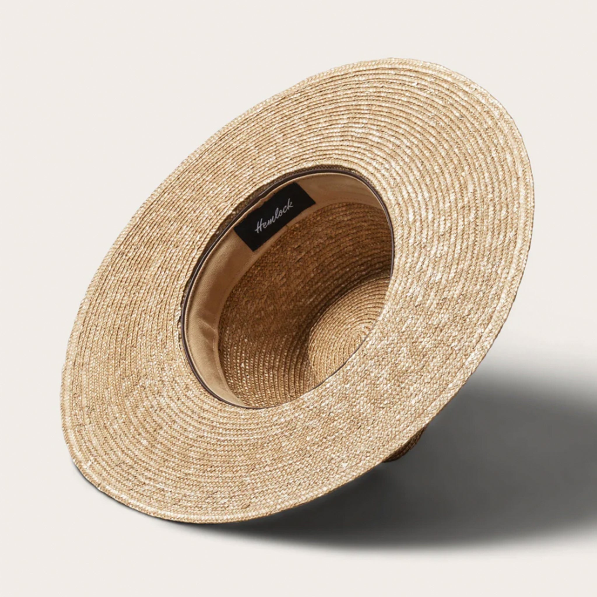 On a white background is a tan woven sun hat with a band around the base of the hat.