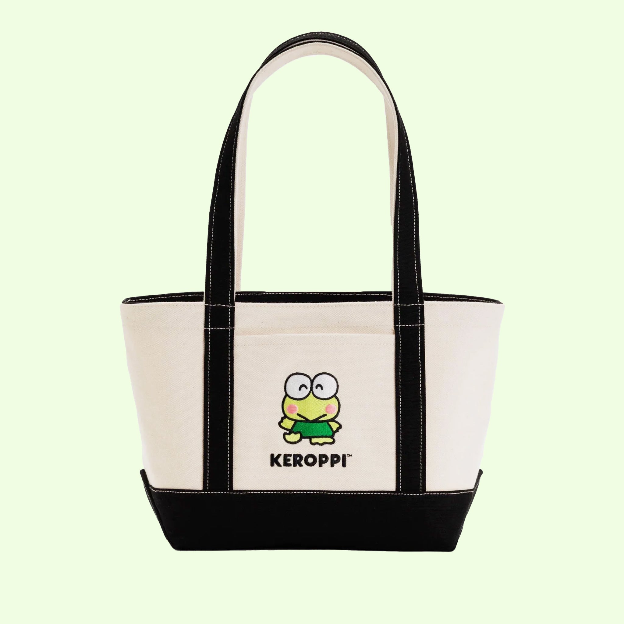 On a light green background is a black and ivory tote bag with an embroidered Keroppi on the front. 