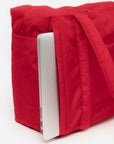 A red small carry on tote bag with two handle straps, front pockets and a zipper closure.