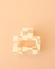 On a peachy background is a square ivory and clear claw clip.