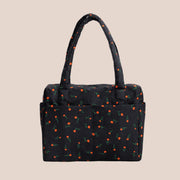 A black nylon puffy carry on tote bag with a red and green wildflower print.