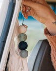 On a peachy background is four wool balls made into an air freshener with a small bottle of fragrance oil.