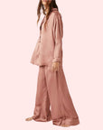 A model wearing an oversized slouchy fit pajama set in a rose gold color.