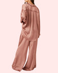 A model wearing an oversized slouchy fit pajama set in a rose gold color.