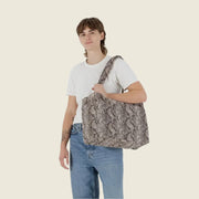 A snakeskin printed nylon cloud carry on.