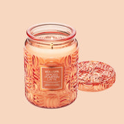 An orange decorative glass jar candle with a lid and a label that reads, 'Voluspa Spiced Pumpkin Latte'.
