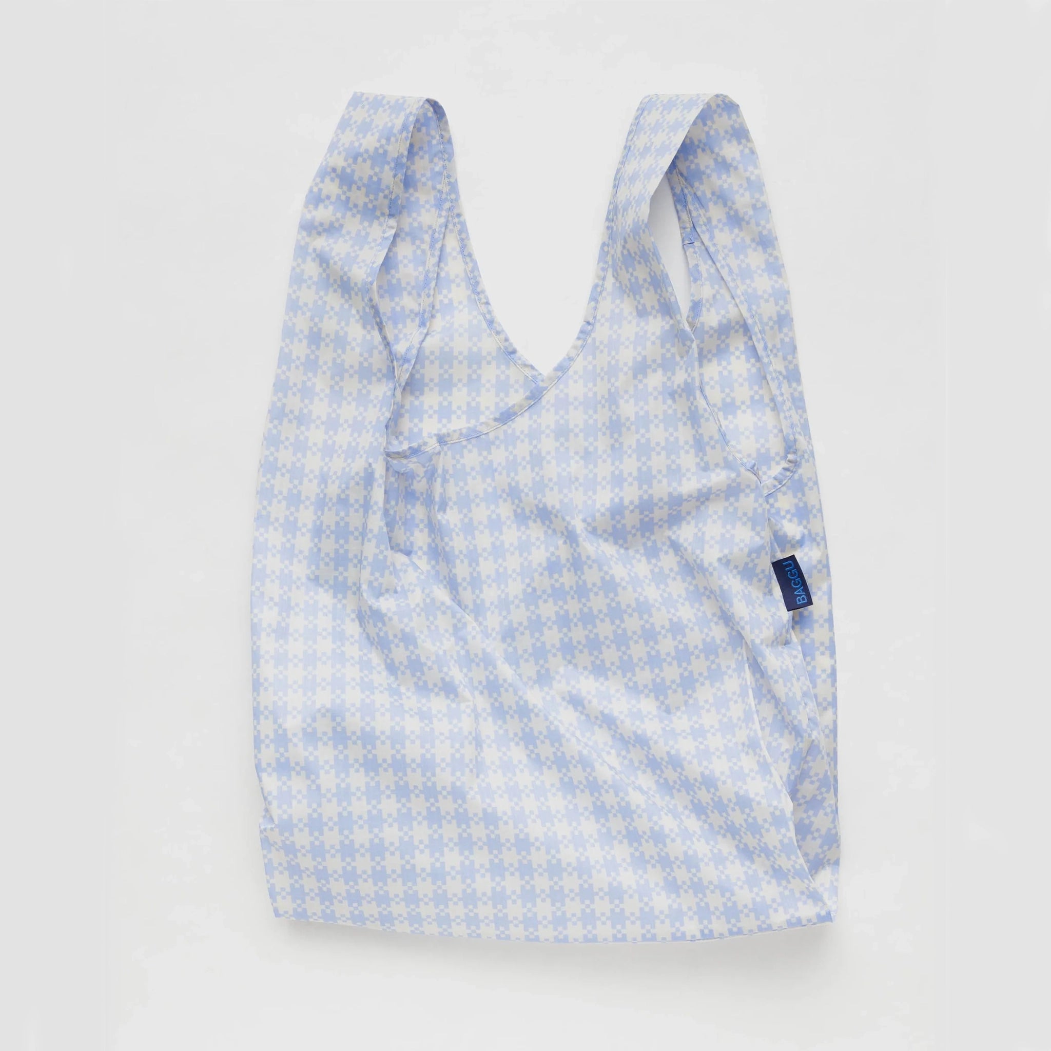 On a white background is a blue and white gingham printed nylon tote bag.