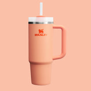 On a salmon pink background is a nectarine orange colored water bottle and straw.
