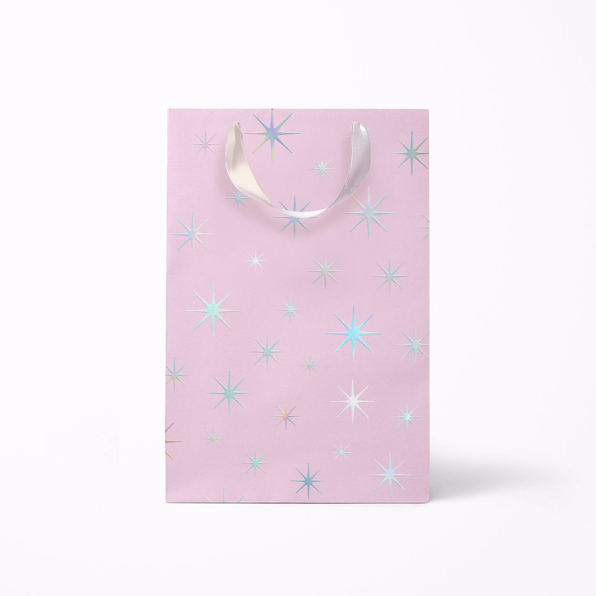 On a white background is a light purple gift bags with a silver star pattern and silver ribbon handles.