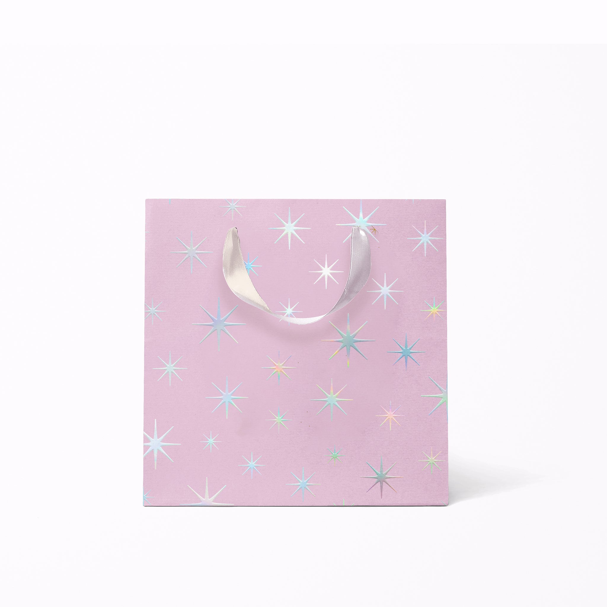 On a white background is a light purple gift bags with a silver star pattern and silver ribbon handles.