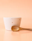 A neutral stoneware bowl with a tiny wooden spoon.