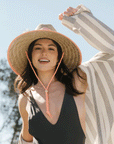 A straw hat with coral details and string neck strap with an adjustable bead.