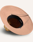 On a white background is a straw hat with a neutral mauve / tan brim underneath and neck strap.