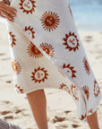 A cream and burnt orange towel with a sun design.