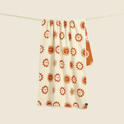 A cream and burnt orange towel with a sun design.