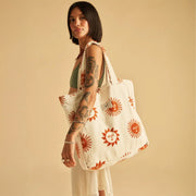 A neutral terry cloth tote bag with a brick red sun design.