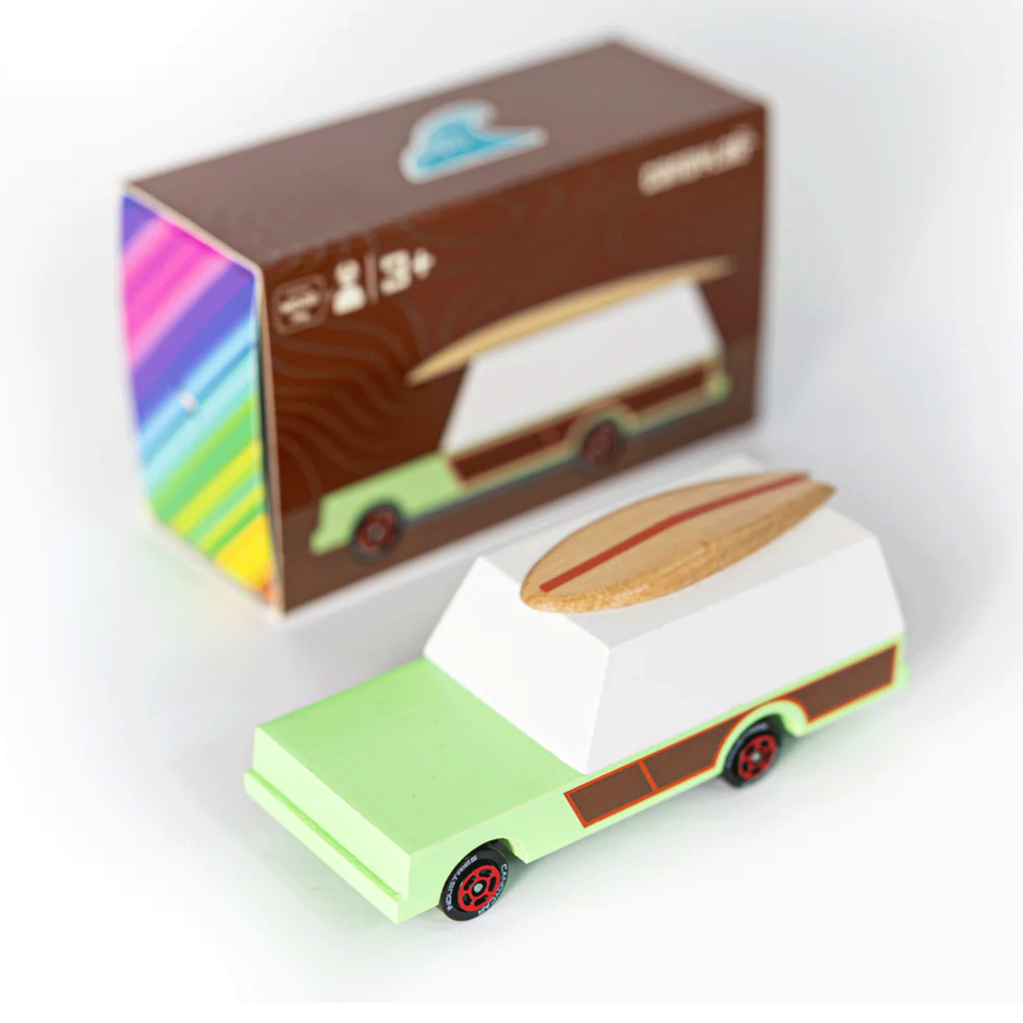 On a white background is a green and and brown station wagon car toy with a wood surf board on top. 