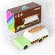 On a white background is a green and and brown station wagon car toy with a wood surf board on top. 