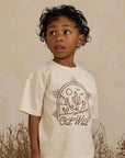 An ivory t-shirt for children with a brown western graphic on the front that reads, "Out West".