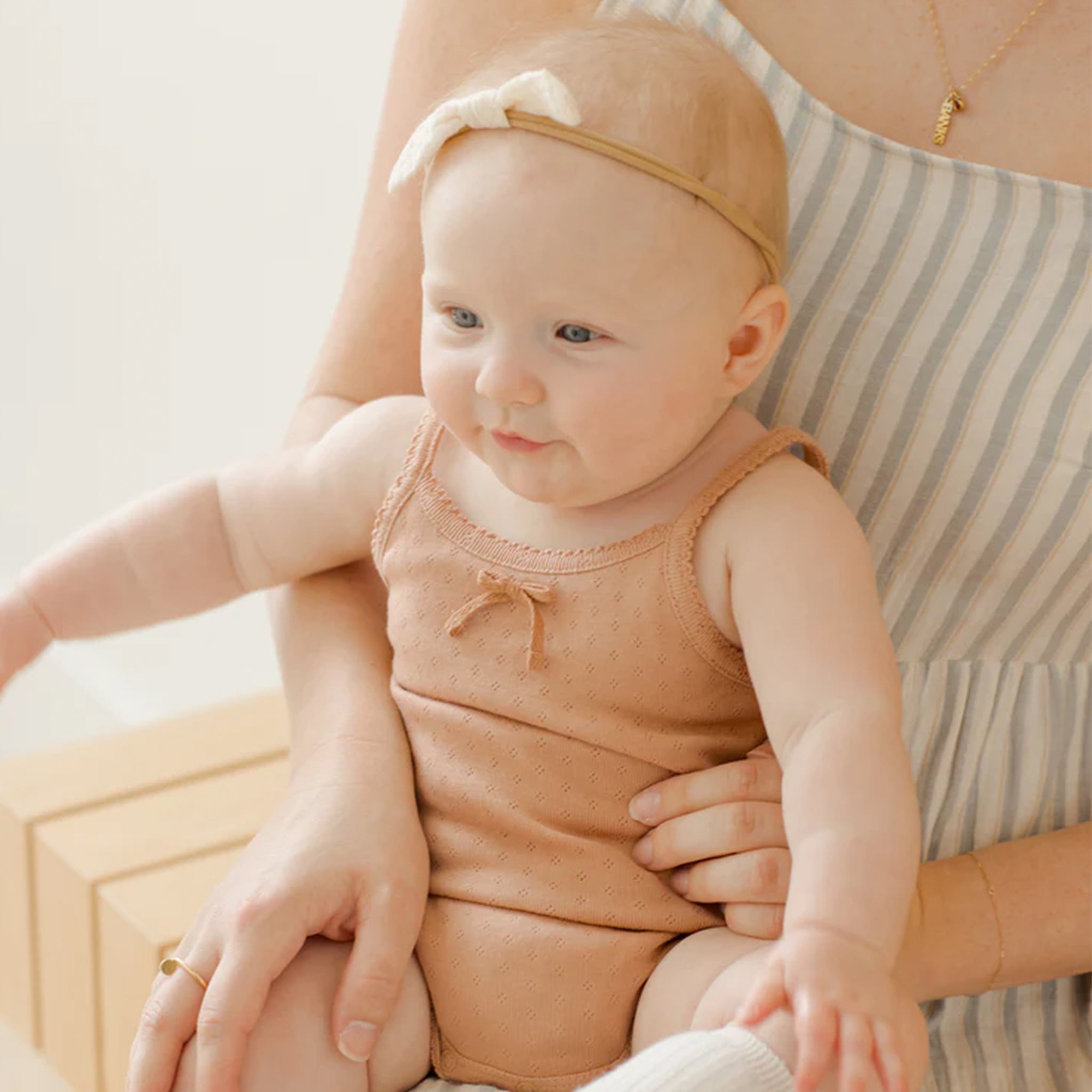 A light orange tank onesie with snap closure and a small bow detail at the top.