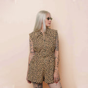 Person wearing a leopard print romper against a beige background